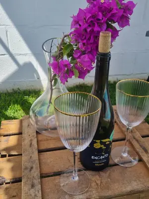 two wine glasses and a bottle and flowers on a wooden table at Villa Encanto in Chiclana de la Frontera