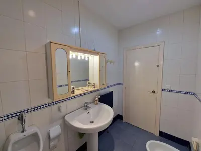 a white bathroom with a sink and a urinal at DULCE CARMEN in Bonanza