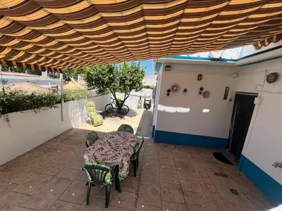 a patio with a table and chairs under a wooden roof at DULCE CARMEN in Bonanza