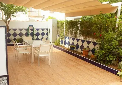 a patio with a table and chairs and an umbrella at Duplex Las Torres La Barrosa 3Beds - A 700m de la playa in Chiclana de la Frontera