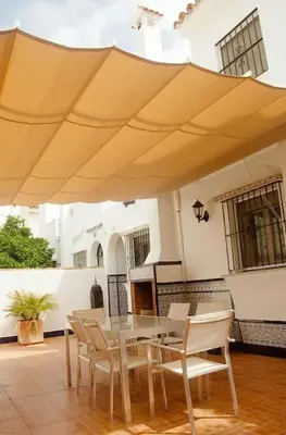 a patio with a table and chairs under a large umbrella at Duplex Las Torres La Barrosa 3Beds - A 700m de la playa in Chiclana de la Frontera