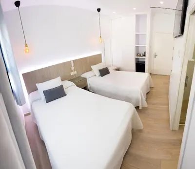 two beds in a hotel room with white sheets at Apartahotel Énfasis-Group in El Cuervo