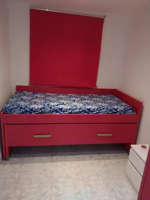 a red bed with a red headboard in a room at piso pilar in Chiclana de la Frontera