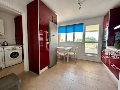 a kitchen with red cabinets and a table with a dining room at Casa La Camelia con Piscina Grupo AC Gestión in El Puerto de Santa María