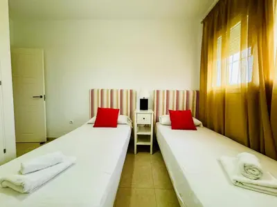 two beds in a room with red pillows at Casa La Camelia con Piscina Grupo AC Gestión in El Puerto de Santa María