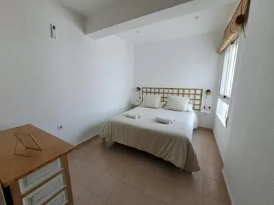 a bedroom with a bed and a desk and a window at Ático primera línea de playa con vistas al Mar-Climatizado-Wifi-Parking-Solo familias in El Puerto de Santa María