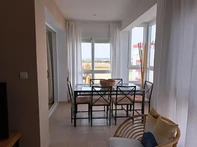 a dining room with a table and chairs and a window at Ático primera línea de playa con vistas al Mar-Climatizado-Wifi-Parking-Solo familias in El Puerto de Santa María