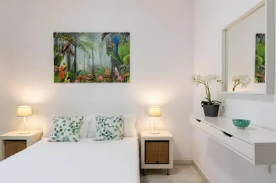 a white bedroom with a bed and two lamps at Casa San Lucas - Corazón del Casco Histórico con piscina y parking in Jerez de la Frontera