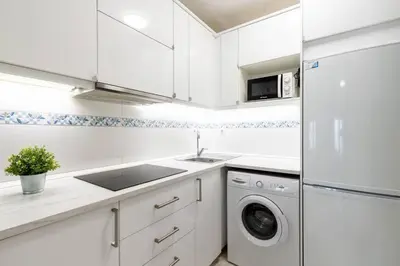 a white kitchen with a sink and a dishwasher at Casa San Lucas - Corazón del Casco Histórico con piscina y parking in Jerez de la Frontera