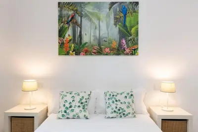 a bedroom with a bed with two lamps and a painting on the wall at Casa San Lucas - Corazón del Casco Histórico con piscina y parking in Jerez de la Frontera