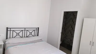 a white bedroom with a bed and a door to a room at Villa nazaret in Chiclana de la Frontera