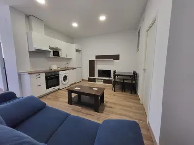 a living room with a blue couch and a table at Apartamento Parque Bahía in Puerto Real