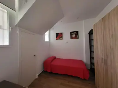 a bedroom with a red bed in a white room at Apartamento Parque Bahía in Puerto Real