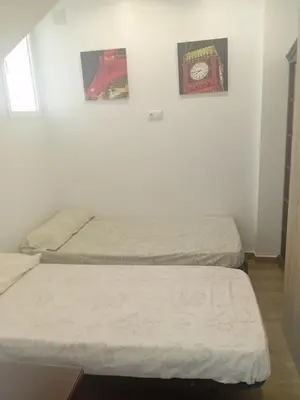 two beds in a room with two posters on the wall at Apartamento Parque Bahía in Puerto Real