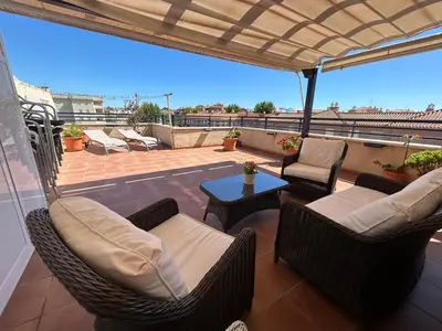 a patio with wicker chairs and a table on a roof at ÁTICO BAJO GUÍA in Sanlúcar de Barrameda