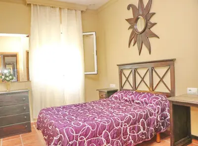 a bedroom with a purple bed and a clock on the wall at Casa El Oasis in Conil de la Frontera
