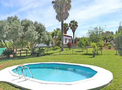 a swimming pool in a yard with trees and a house at Casa El Oasis in Conil de la Frontera