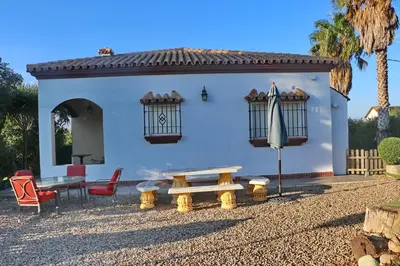 a white house with a picnic table and an umbrella at Casa El Oasis in Conil de la Frontera