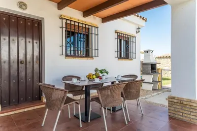 a patio with a table and chairs and a stove at EntreCalas 2 Chalet con piscina privada en Conil, Roche viejo, cala del aceite in Conil de la Frontera