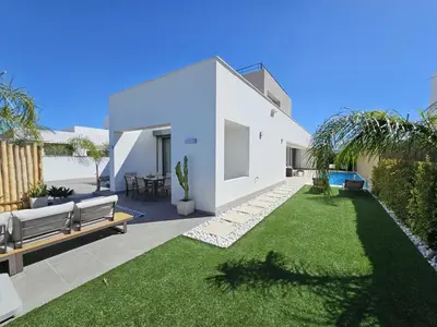 a backyard with a white house with a lawn at La Casetta de Conil junto a la playa in Conil de la Frontera