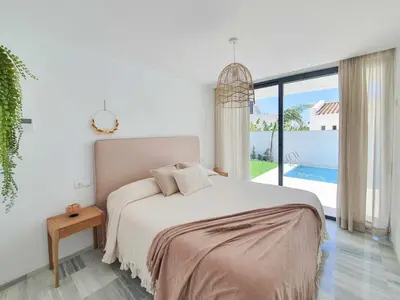 a white bedroom with a bed and a large window at La Casetta de Conil junto a la playa in Conil de la Frontera