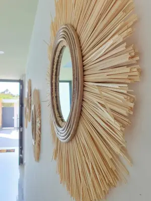 a mirror hanging on a wall with wooden sticks at La Casetta de Conil junto a la playa in Conil de la Frontera