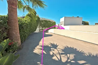 a sidewalk with a pink string next to a palm tree at On Beach Deluxe Apartment with Pools and own Garden in El Puerto de Santa María