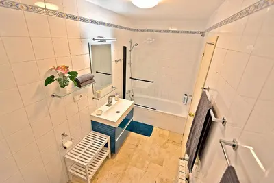 a white bathroom with a sink and a shower at On Beach Deluxe Apartment with Pools and own Garden in El Puerto de Santa María