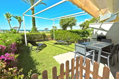 a backyard with a table and chairs and a fence at On Beach Deluxe Apartment with Pools and own Garden in El Puerto de Santa María