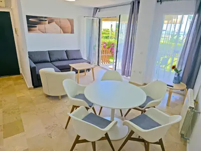 a living room with a table and chairs and a couch at On Beach Deluxe Apartment with Pools and own Garden in El Puerto de Santa María