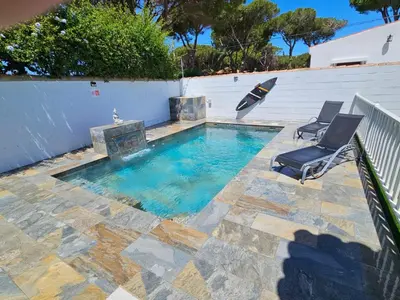 a swimming pool with two chairs and an umbrella at Casa piscina in Chiclana de la Frontera