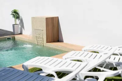a group of white lounge chairs next to a swimming pool at Bisonte A in Chiclana de la Frontera
