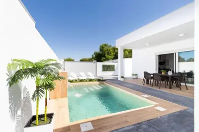 a villa with a swimming pool and a dining area at Bisonte A in Chiclana de la Frontera