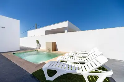 a group of white lounge chairs next to a swimming pool at Bisonte A in Chiclana de la Frontera