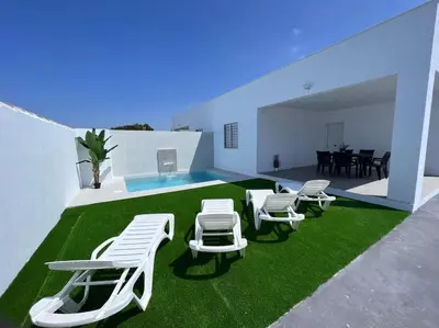 a room with white chairs and a table and grass at GRANIZO A in Chiclana de la Frontera