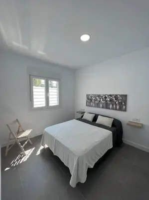 a bedroom with a bed and a chair and a window at GRANIZO A in Chiclana de la Frontera
