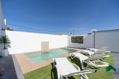 a backyard with a pool and white chairs and a swimming pool at Bisonte B in Chiclana de la Frontera