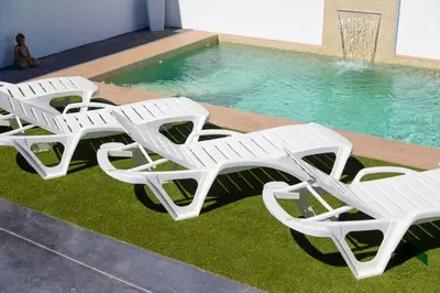 a group of white lounge chairs next to a swimming pool at Bisonte B in Chiclana de la Frontera