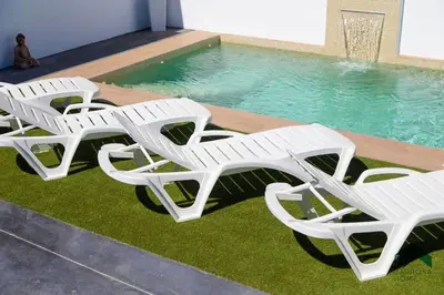 a group of white lounge chairs next to a swimming pool at Bisonte C in Chiclana de la Frontera