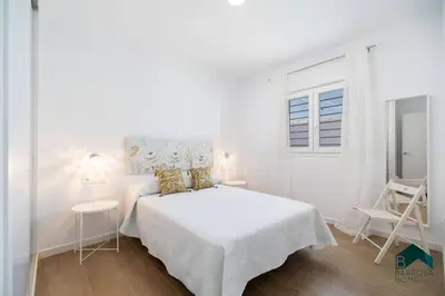 a white bedroom with a bed and two chairs at Bisonte C in Chiclana de la Frontera