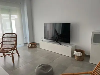 a living room with a large tv and a chair at La casa de Pepo in Conil de la Frontera