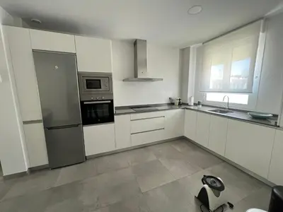 a kitchen with white cabinets and stainless steel appliances at La casa de Pepo in Conil de la Frontera