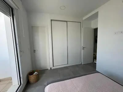 a bedroom with white cabinets and a pink rug at La casa de Pepo in Conil de la Frontera