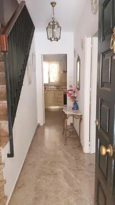 a hallway with a table and a chandelier at Casa Carmen in Sanlúcar de Barrameda