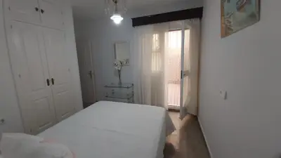 a white bedroom with a bed and a window at Casa Carmen in Sanlúcar de Barrameda