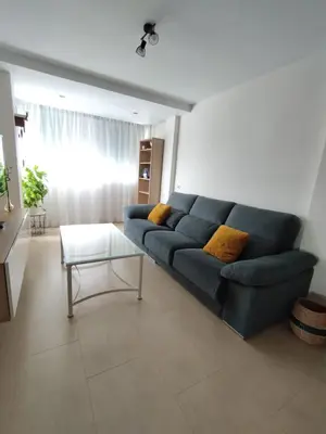 a living room with a blue couch and a table at Apartamento en Jerez 3 dormitorios y 2 baños in Jerez de la Frontera