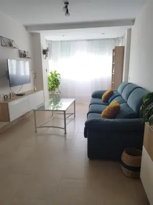 a living room with a blue couch and a glass table at Apartamento en Jerez 3 dormitorios y 2 baños in Jerez de la Frontera