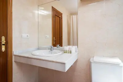 a bathroom with a sink and a toilet and a mirror at Apartoyou - Soto de Vistahermosa in El Puerto de Santa María