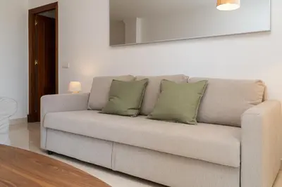 a couch with three pillows on it in a living room at Apartoyou - Soto de Vistahermosa in El Puerto de Santa María