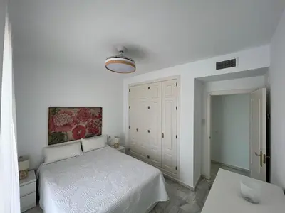 a white bedroom with a bed and a table at costa ballena elite in Costa Ballena